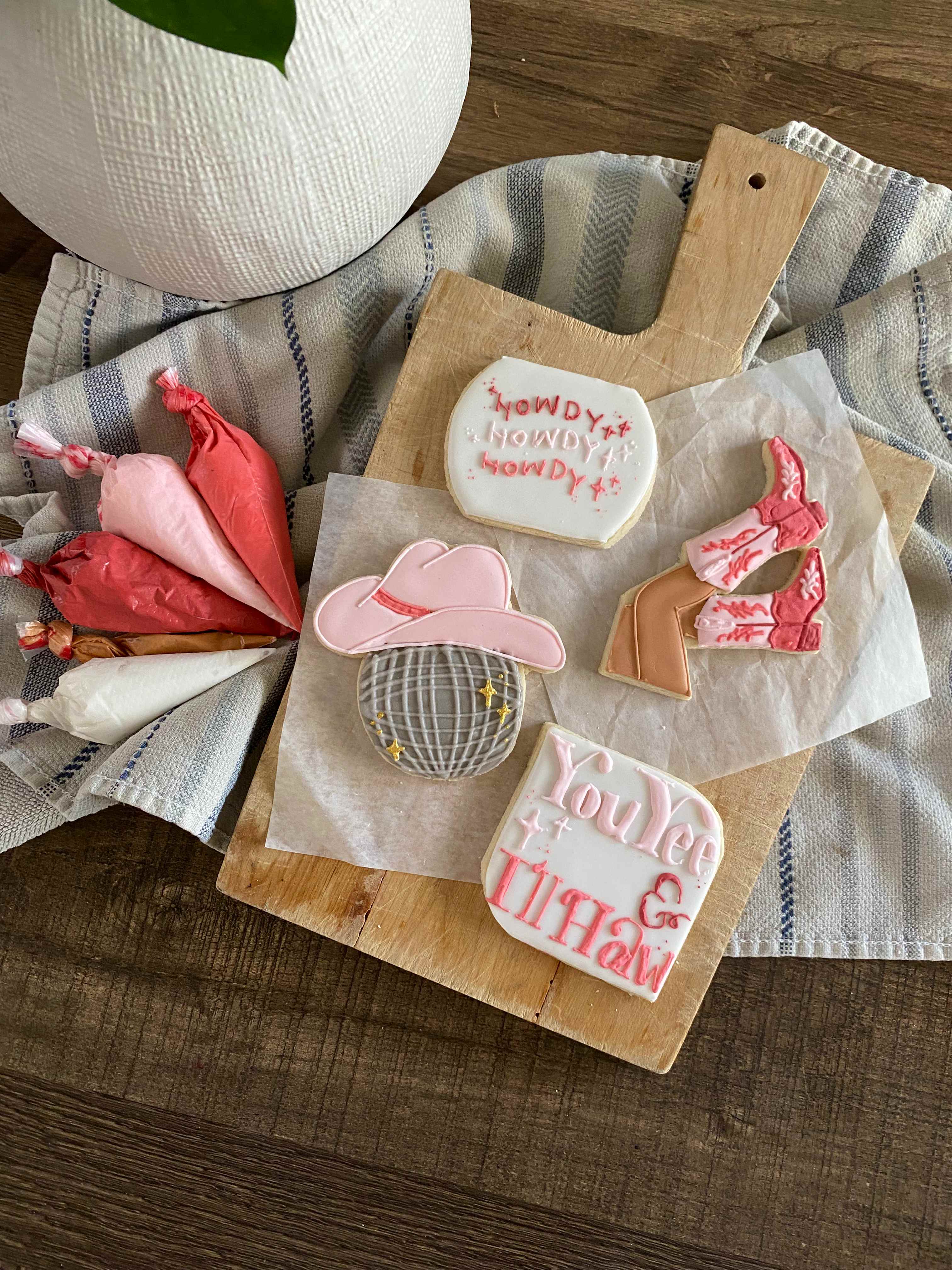 Western themed cookies with pink cowboy hat, disco ball, cowboy boots, and Howdy text
